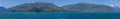 A panorama view along the forested shoreline of the Gastineau Channel approaching Juneau, Alaska