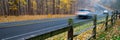 Panorama view busy traffic on curved winding country road cars traffic along wooden fence, colorful fall foliage leaves carpet Royalty Free Stock Photo