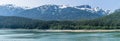 A panorama view of the densely forested shoreline in the Gastineau Channel on the approach to Juneau, Alaska