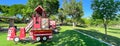 Panorama view firetruck themed playground with green artificial grass turf carpet by tall mature trees clear blue sky in