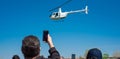 Panorama view hands taking photo hovering helicopter drops colorful eggs and goodies at Easter event in Richardson