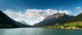 Panorama view of an idyllic and picturesque turquoise mountain lake surrounded by green forest and mountain peaks in the Swiss