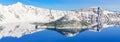 Panoramic scenic winter mirror reflection of snowcap mountain and Wizard Island on Crater Lake Royalty Free Stock Photo