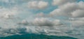 Panorama view of the overcast sky above the green mountain and electric pylons. Dramatic sky and cumulus clouds. Cloudy and moody