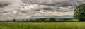 A panorama view of Pendle Hill and farm land with rain clouds.