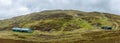 A panorama view of a Scottish ski resort with green slope, cafe and ski lift under a grey sky Royalty Free Stock Photo