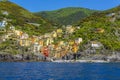 A panorama view from the sea across the harbour breakwater towards the Cinque Terre village of Riomaggiore, Italy Royalty Free Stock Photo