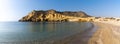 Panorama view of a secluded cove and beach on the Meiterranean coast of Spain with caves and sandstone cliffs behind