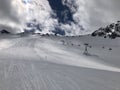 Panorama view of ski resort with slope, people on the ski lift, skiers on the piste among white snow