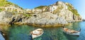 A panorama view of small fishing boats moored in front of the village of Manarola, Cinque Terre, Italy Royalty Free Stock Photo