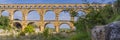 Panorama view to the limestone Pont du Gard three-tiered aqueduct at the river Gardon. Royalty Free Stock Photo