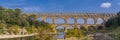 Panorama view to the limestone Pont du Gard three-tiered aqueduct at the river Gardon. Royalty Free Stock Photo