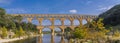 Panorama view to the limestone Pont du Gard three-tiered aqueduct at the river Gardon. Royalty Free Stock Photo