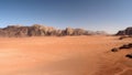 Panorama of the WadiRum desert surrounded by red rock mountains with blue sky