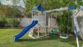 Panorama Whispy white clouds Small set of playground on a green lawn at the fenced backyard a Royalty Free Stock Photo