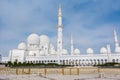 Panorama of White Grand Mosque with fence against blue sky, also called Sheikh Zayed Grand Mosque, inspired by Persian, Mughal and