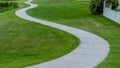 Panorama Winding footpath along a shiny pond in front of homes viewed on a sunny day