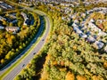 Panorama winding road along residential quarters of a small town among the autumn forest