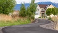 Panorama Winding road leading to distant homes with mountain and cloudy sky background