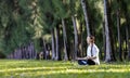 Panorama of woman relaxingly practicing meditation in the pine forest to attain happiness from inner peace wisdom for healthy mind