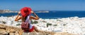 Woman sitting on a hill over the white town of Mykonos island