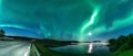 Panoramci Aurora borealis, Northern green lights with full moon and stars in the night sky over mountain lake, mirrored reflection Royalty Free Stock Photo