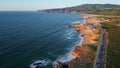 Panoramic aerial coast road near ocean shoreline washing by turquoise waves.