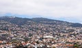 Panoramic aerial view of funchal in madeira with buildings running up the hills and white clouds above the mountains