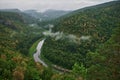 Panoramic aerial view over the top of a summer landscape of a green hills, a large river, and a forest belt at sunset Royalty Free Stock Photo