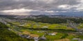 Panoramic aerial view of shafts of light breaking through storm clouds over farmland