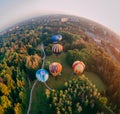 Panoramic air view of hot air ballons prepare for an early morning takeoff from park in small european city Royalty Free Stock Photo