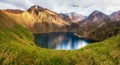 Panoramic alpine landscape with mountain lake in green valley and glacier under cloudy sky. Atmospheric highland scenery with Royalty Free Stock Photo