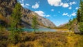 Panoramic alpine landscape with mountain lake in green valley in summer under blue sky. Awesome highland scenery with beautiful Royalty Free Stock Photo