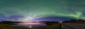 Panoramic Aurora borealis, Northern green lights with full moon and stars in the night sky over mountain lake, mirrored reflection Royalty Free Stock Photo