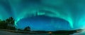 Panoramic Aurora borealis, Northern green lights with lot stars in the night sky over mountain road in mountains, mirrored