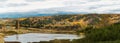 Panoramic autumn landscape. Village and water tower on the shore of the lake. There is a mixed forest on the mountains, Royalty Free Stock Photo