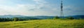 Panoramic banner of industrial communication tower for signal transmitter in a sunny meadow