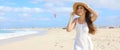 Panoramic banner view of happy young woman holding her straw hat walking on desert beach in a windy day Royalty Free Stock Photo