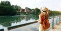 Panoramic banner view of traveler girl with backpack and hat looking castle in the park. Young woman relaxing on Po promenade