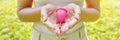 Panoramic banner view of young woman hands holding pink menstrual cup outdoor. Alternative ecological solution for feminine