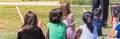 Panoramic close-up rear view multicultural children on grass meadow of outdoor game