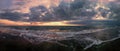 Panoramic cloudy sunset at the beach with dramatic sky and dark stratocumulus clouds with orange sunlight, dark sand with rough Royalty Free Stock Photo