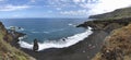 Panoramic coastal landscape, view of the bay, people on the beach with black volcanic sand, waves of Atlantic ocean and blue sky