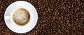 Panoramic coffee background of a cup of black coffee covered with coffee bubble on roasted arabica coffee beans