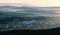 A panoramic countryside of the Hutsul mountain settlement with forests and hills opens from the mountain.