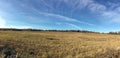 Panoramic countryside landscape with field and forest at far under beautiful blue sky with many white clouds in golden autumn Royalty Free Stock Photo