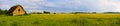 Panoramic countryside wide view of old ruined house with trees behind.