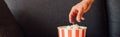 Crop of man reaching popcorn in bucket