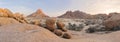 Panoramic, desert landscape of famous rounded red, granite rocks of Spitzkoppe area in early sunrise against blue sky. Picturesque Royalty Free Stock Photo