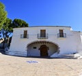 Panoramic front view of Ermita de la Magdalena among pine trees and its tiled main entrance on a sunny day